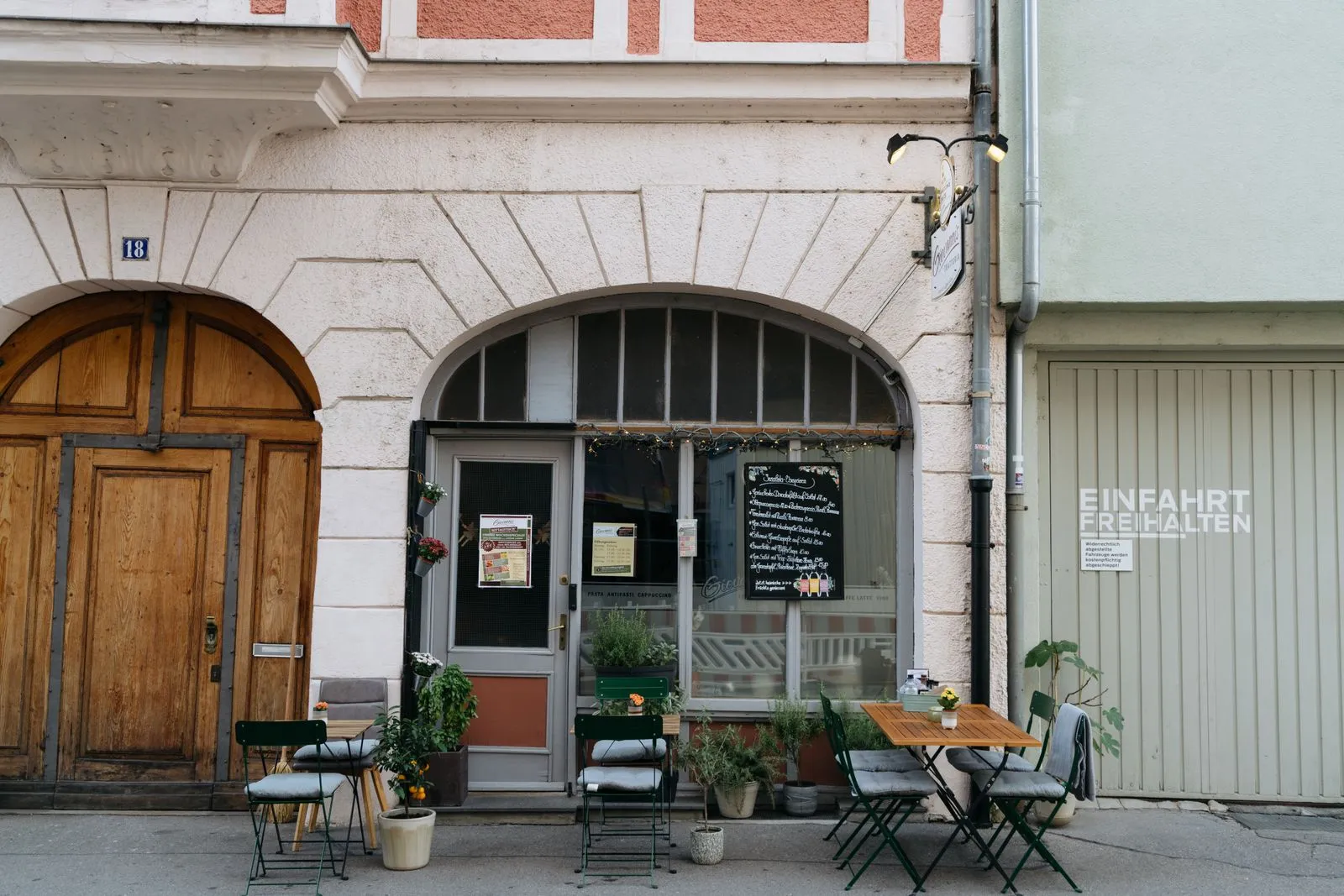 A cozy outdoor cafe setup in a European city with a rustic facade, wooden door, and quaint tables.